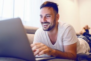 Mann ligger på mange og bruker PC
